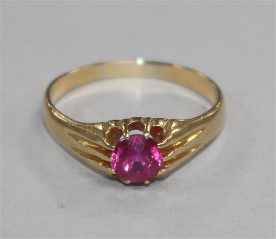 An 18ct gold and synthetic ruby ring, the circular cut stone set between channel-set shoulders, size V.